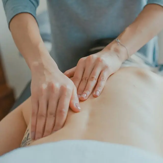 Therapist’s hands massaging a client’s lower back