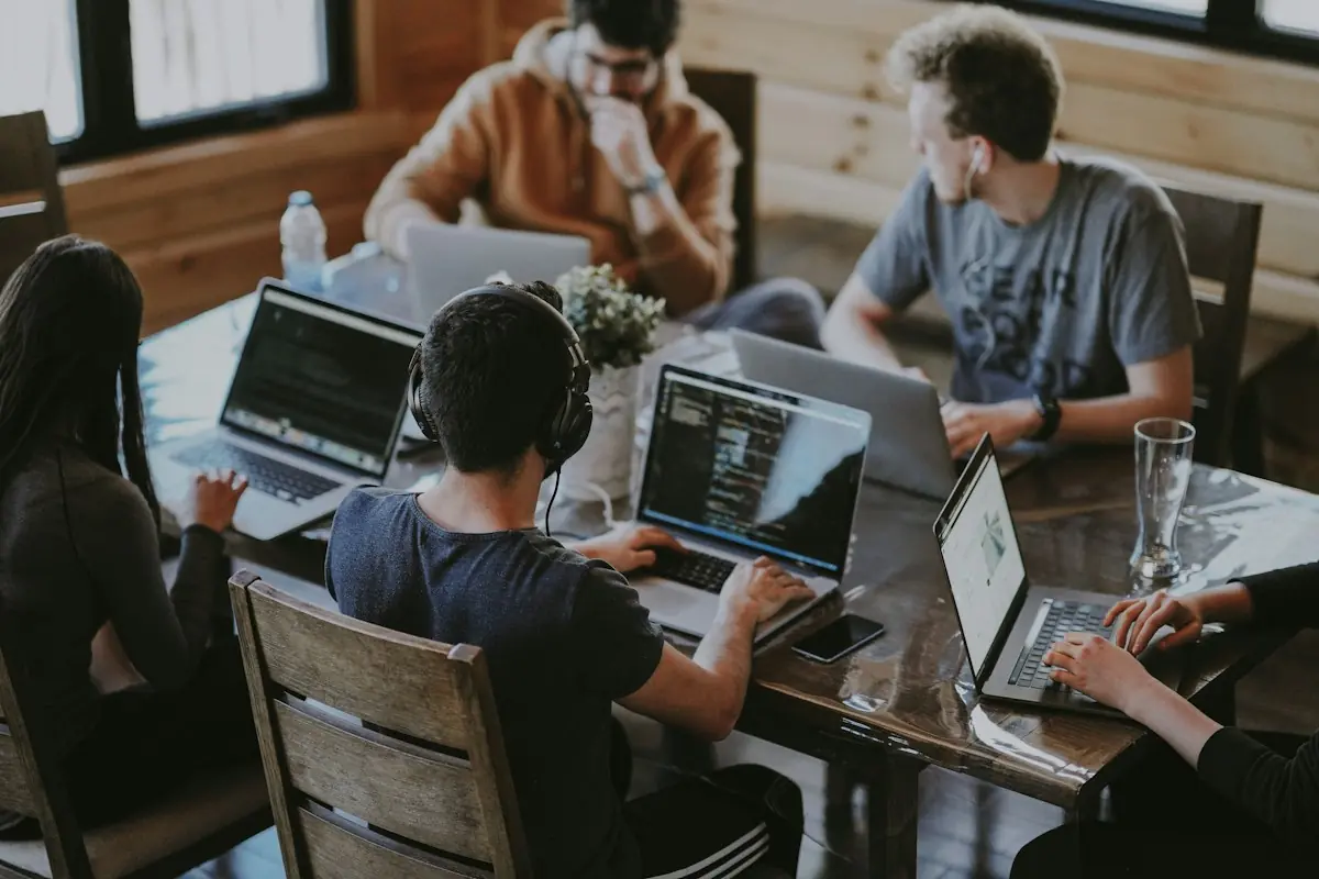 Small startup team working on laptops around a wooden table