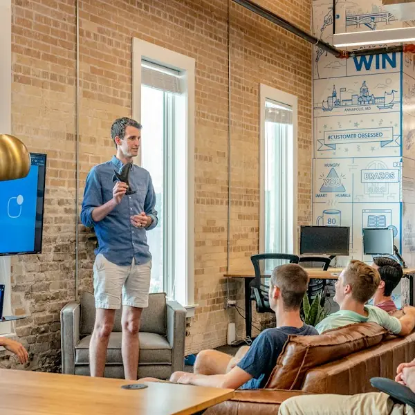 Founder presenting to a small team in a brick-walled space