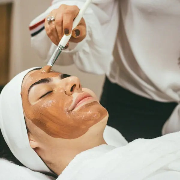 Esthetician applying a clay facial mask