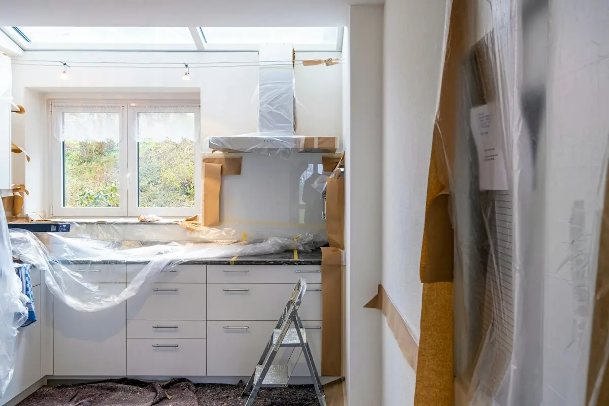 Kitchen mid-remodel with cabinets covered in protective plastic