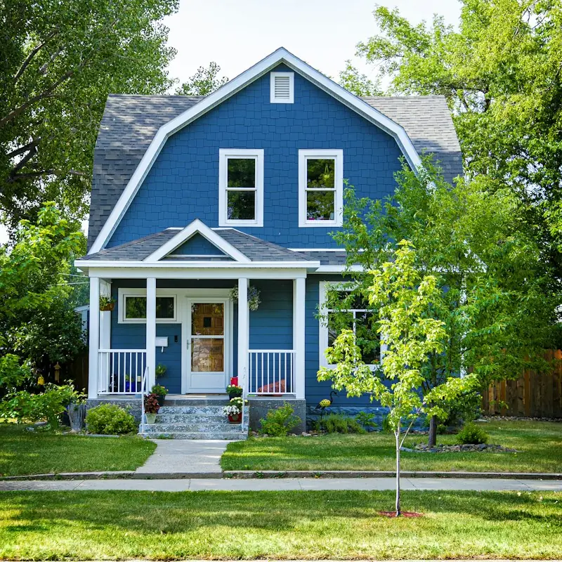 Two-story house painted deep blue with crisp white trim and a white porch railing