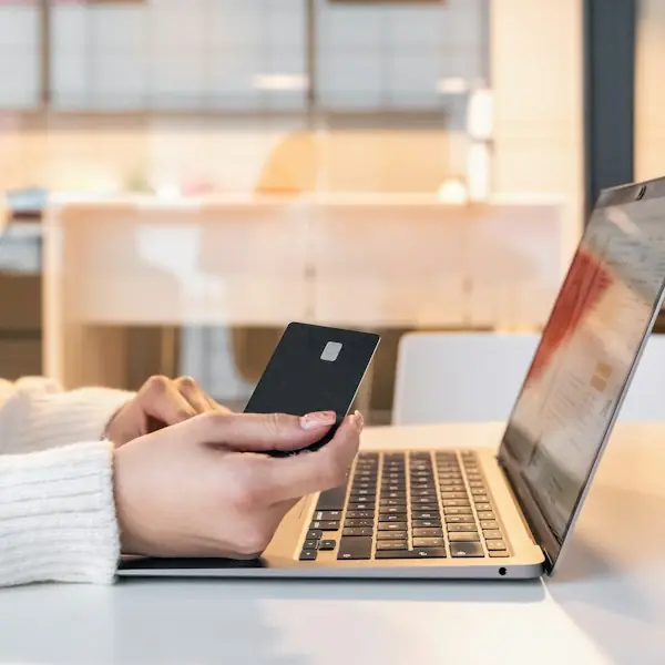 Shopper holding a card while buying on a laptop