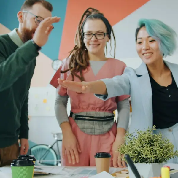 Team high-fiving around a desk in a colorful office